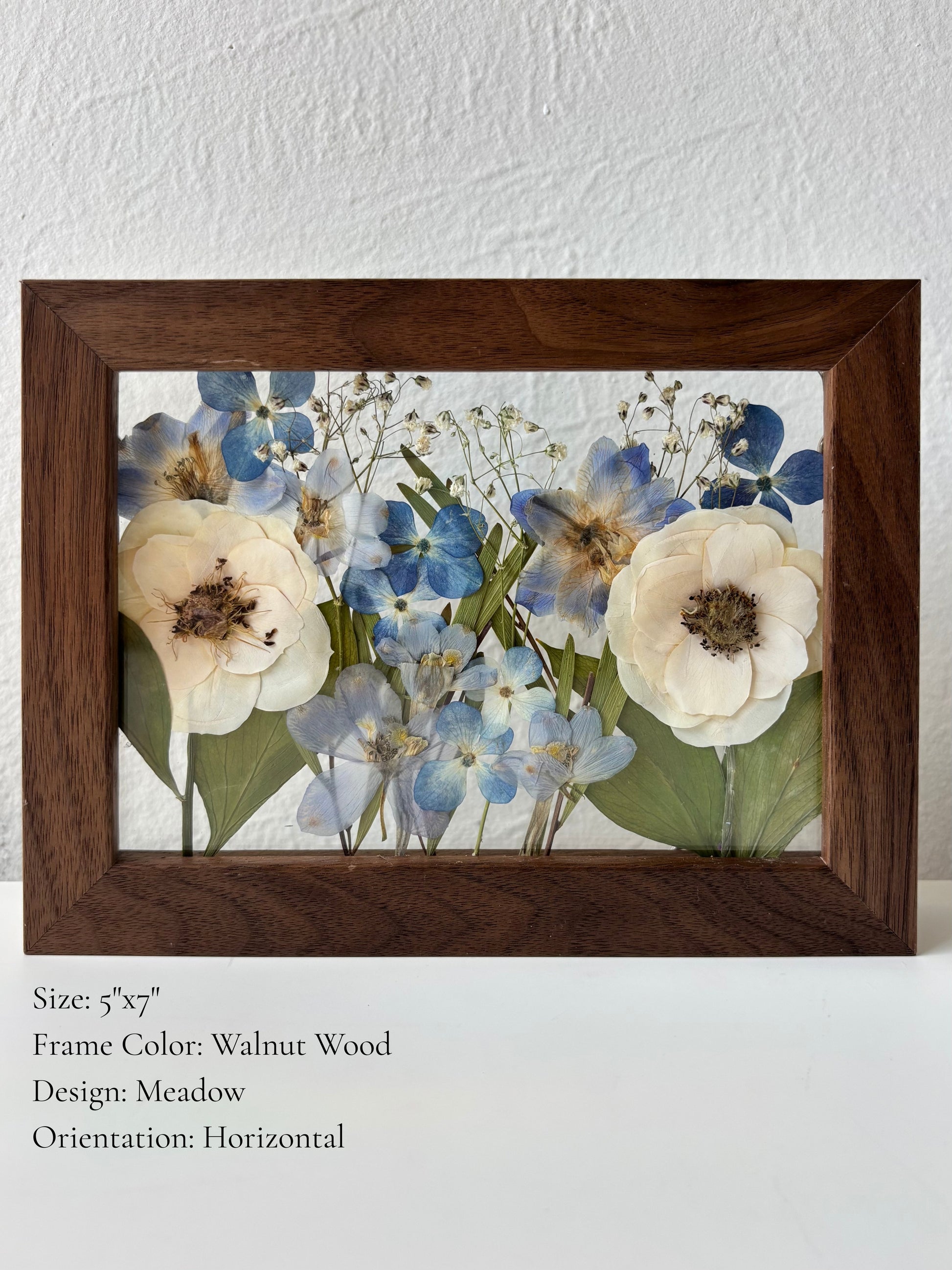 Floating glass walnut wood frame with custom pressed bridal flowers in a meadow or garden style.
