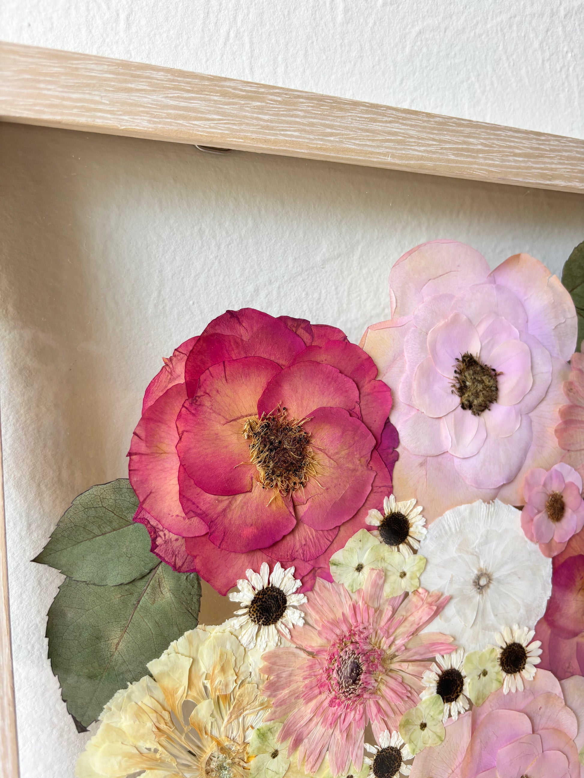 A close up of a wedding or memorial flowers preserved in a large natural wooden floating frame.