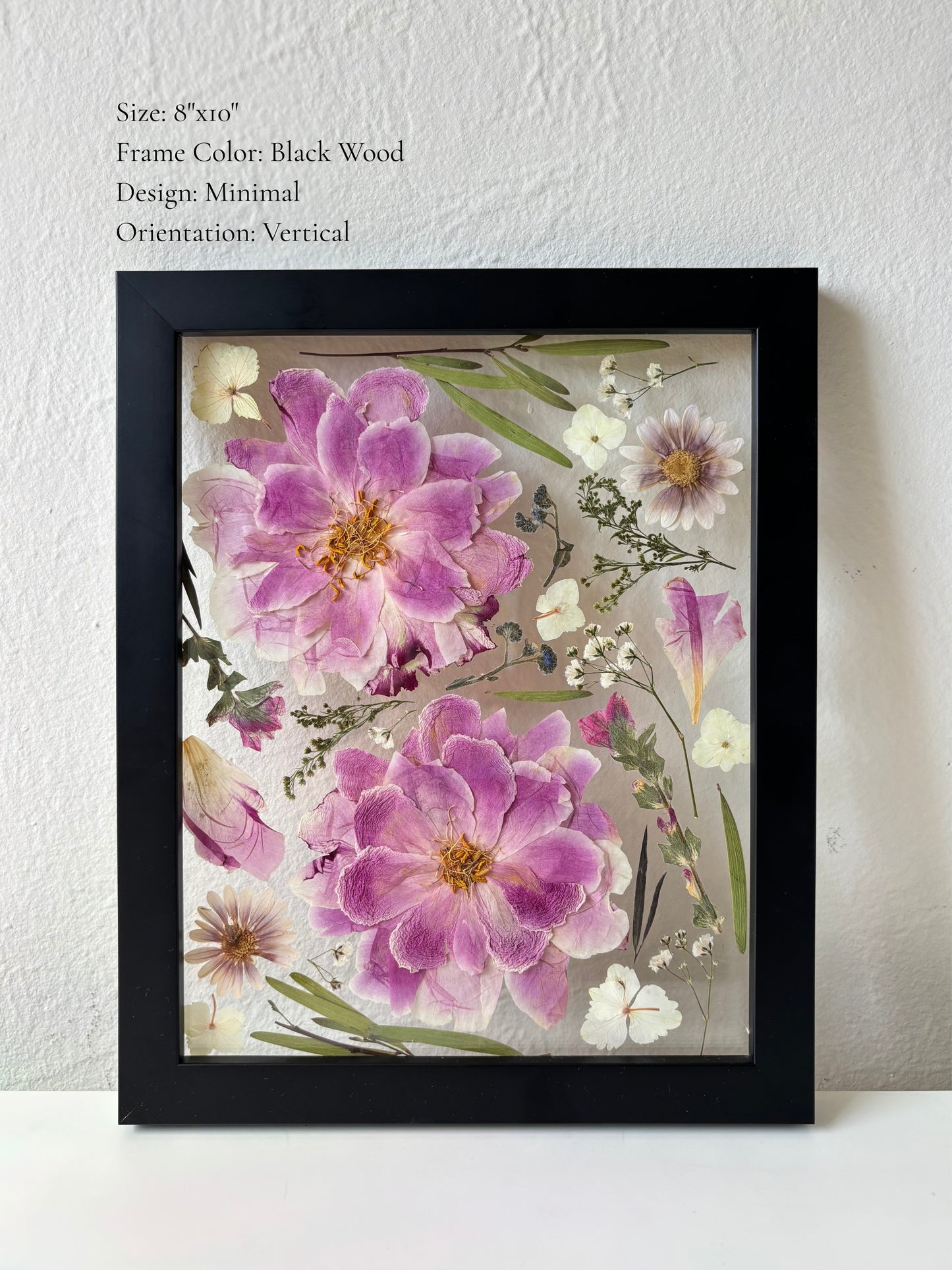 Wedding flowers pressed and arranged in black floating frame in a minimalist style.