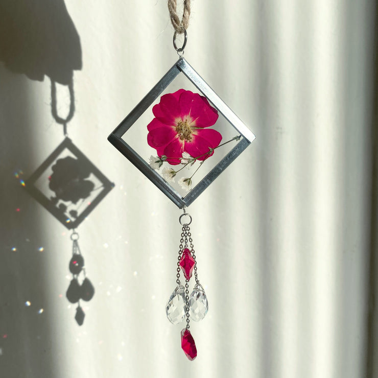 Handmade pressed flower sun catcher with hanging crystals for red car decor.