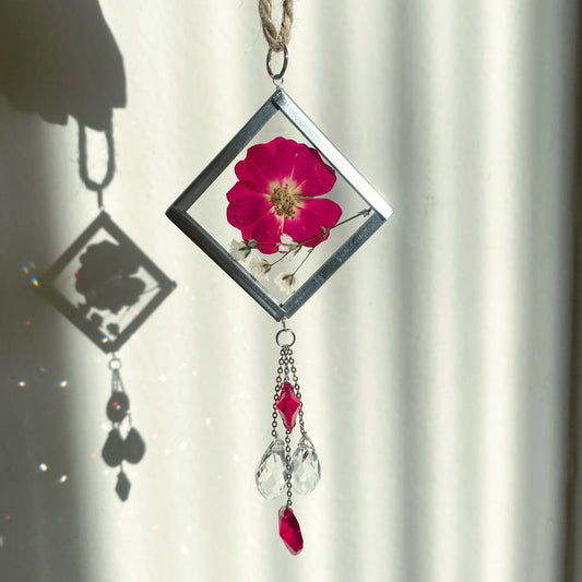 Handmade pressed flower sun catcher with hanging crystals for red car decor.