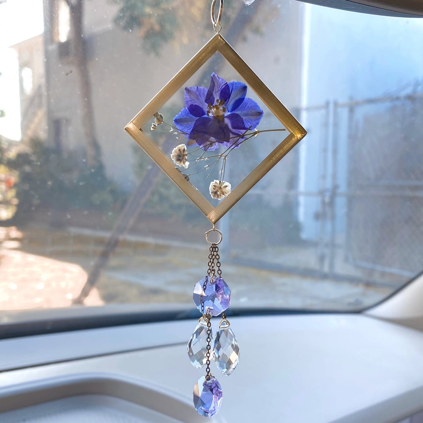 Purple girly car decor. A handmade sun catcher with a purple pressed flower and clear crystals, hanging from a car's rear view mirror.
